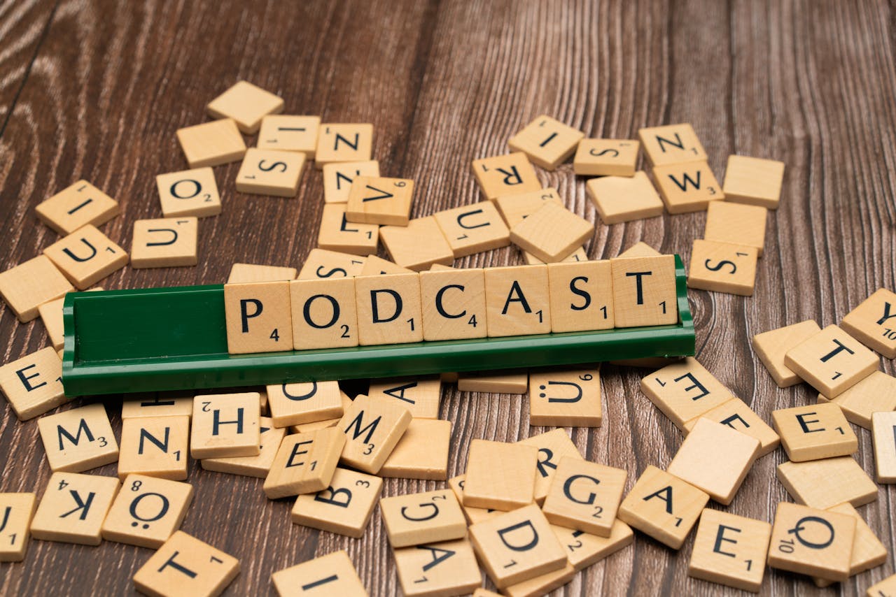 Wooden letter tiles on a board spelling the word Podcast, symbolizing digital media and creativity.